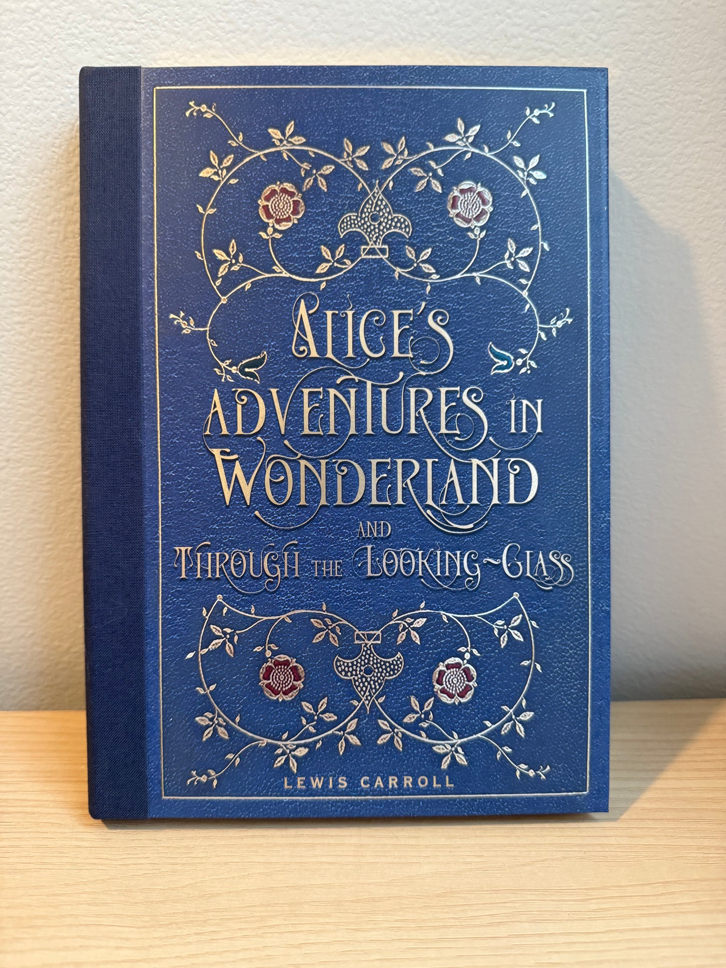 Blue book cover of 'Alice's Adventures in Wonderland' with decorative text and illustrations.