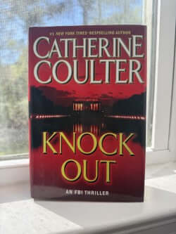 Book titled 'Knock Out' by Catherine Coulter on a windowsill.