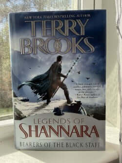 Book titled 'Legends of Shannara: Bearers of the Black Staff' by Terry Brooks on a white surface with a blurred background.