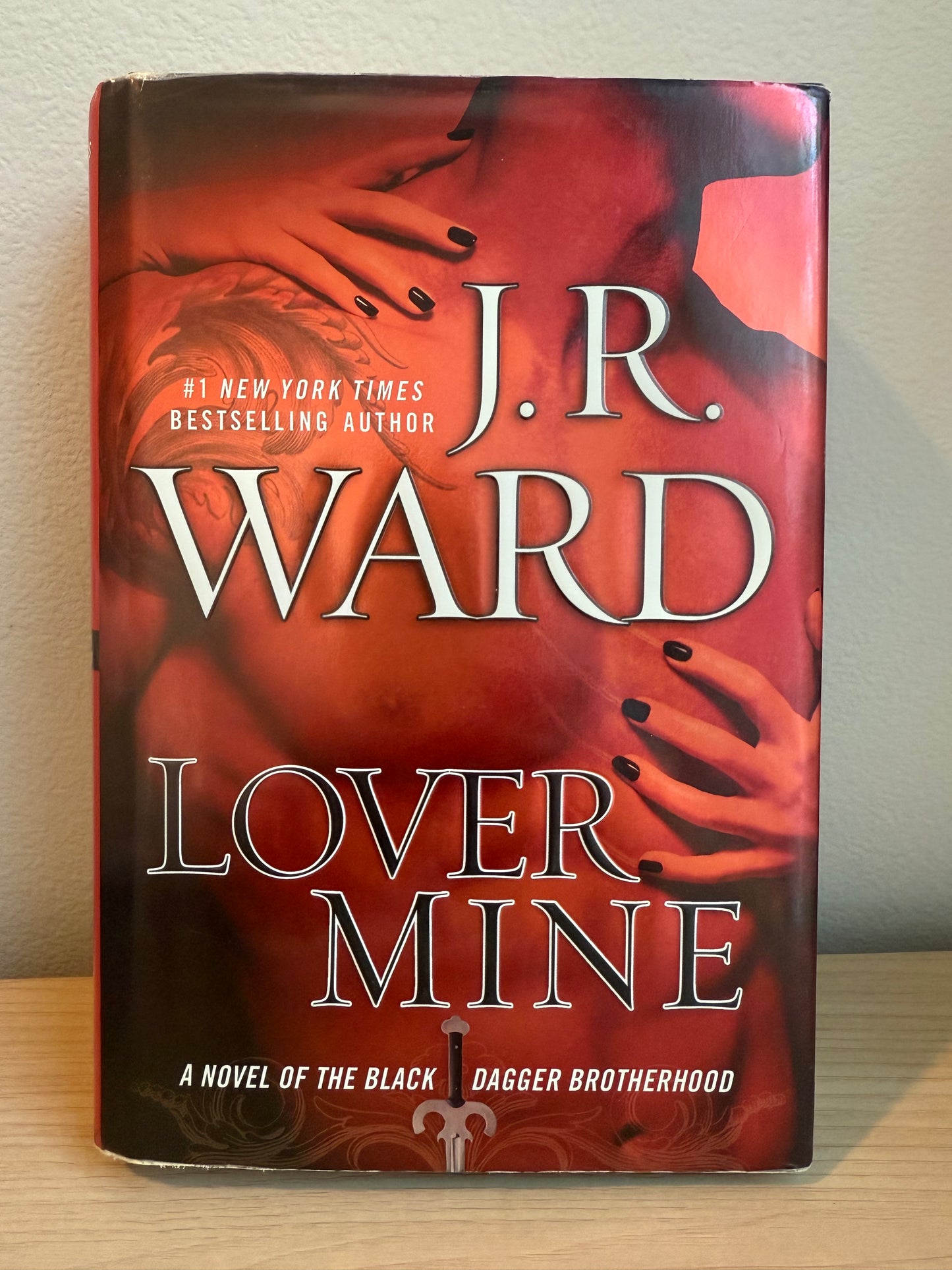 Book titled 'Lover Mine' by J.R. Ward on a light wooden surface.