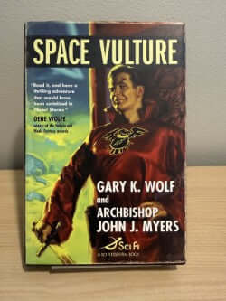 Book cover of 'Space Vulture' by Gary K. Wolf and Archbishop John J. Myers on a wooden surface.