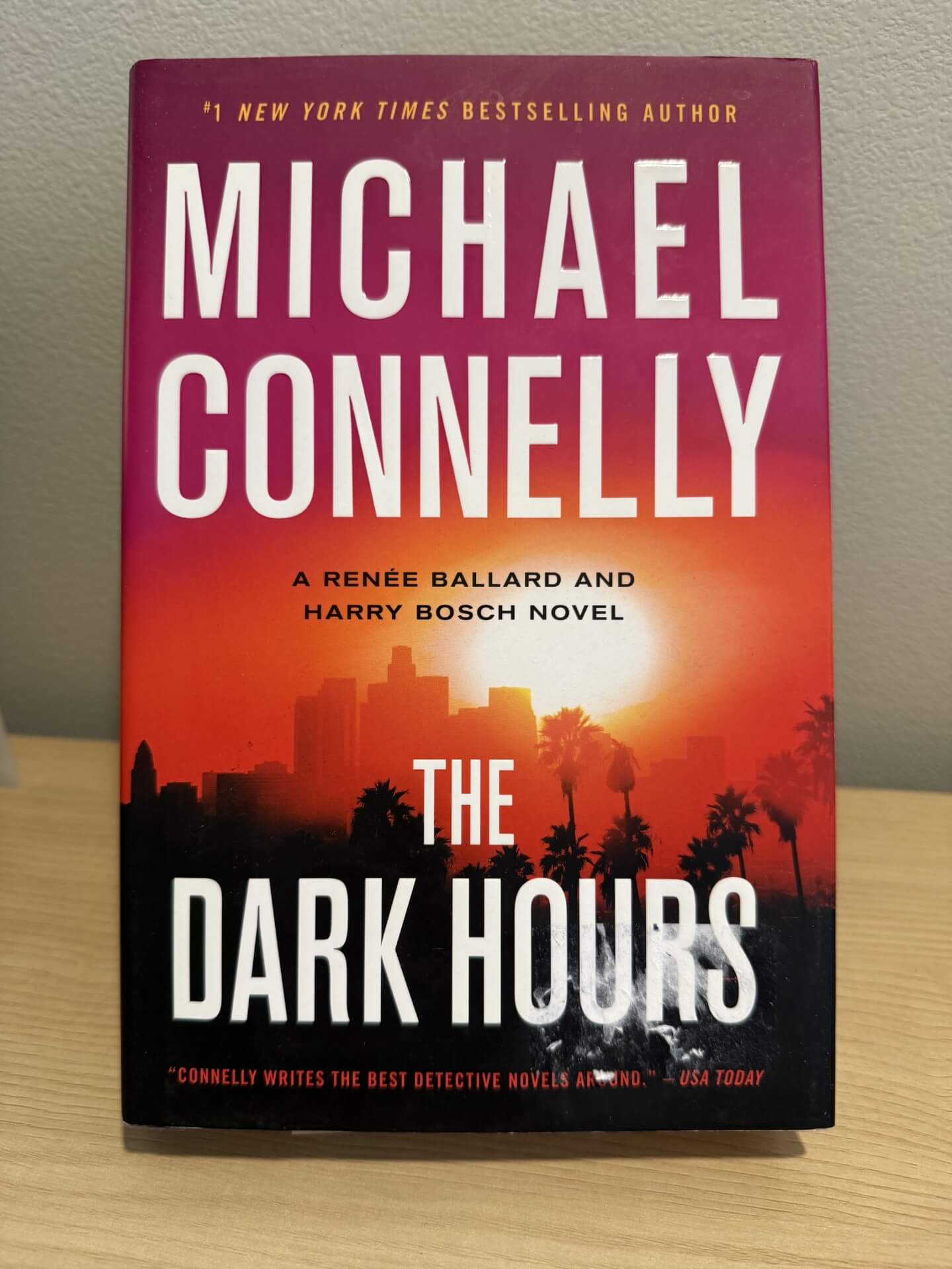 Book titled 'The Dark Hours' by Michael Connelly on a wooden surface with a blurred background