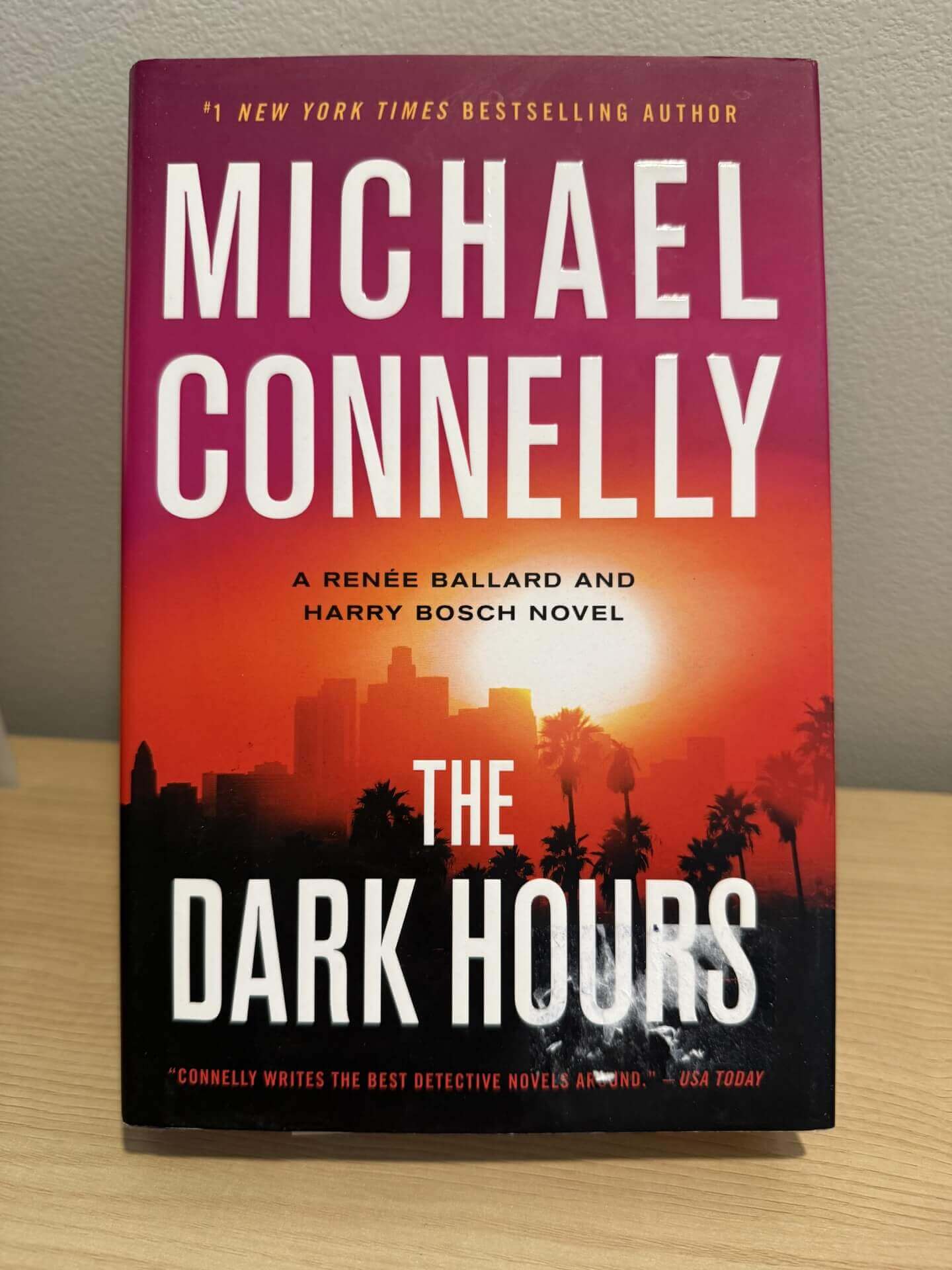 Book titled 'The Dark Hours' by Michael Connelly on a wooden surface with a blurred background