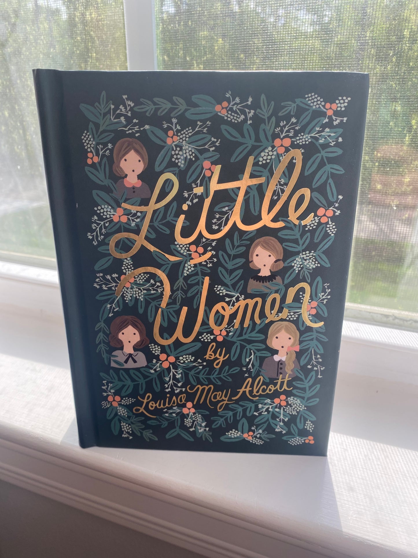 A book cover of 'Little Women' by Louisa May Alcott, featuring illustrations of the main characters, Meg, Jo, Beth, and Amy, set against a floral patterned background.