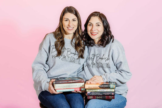 Two women in matching sweaters holding books for the 'New Year New Books' article.