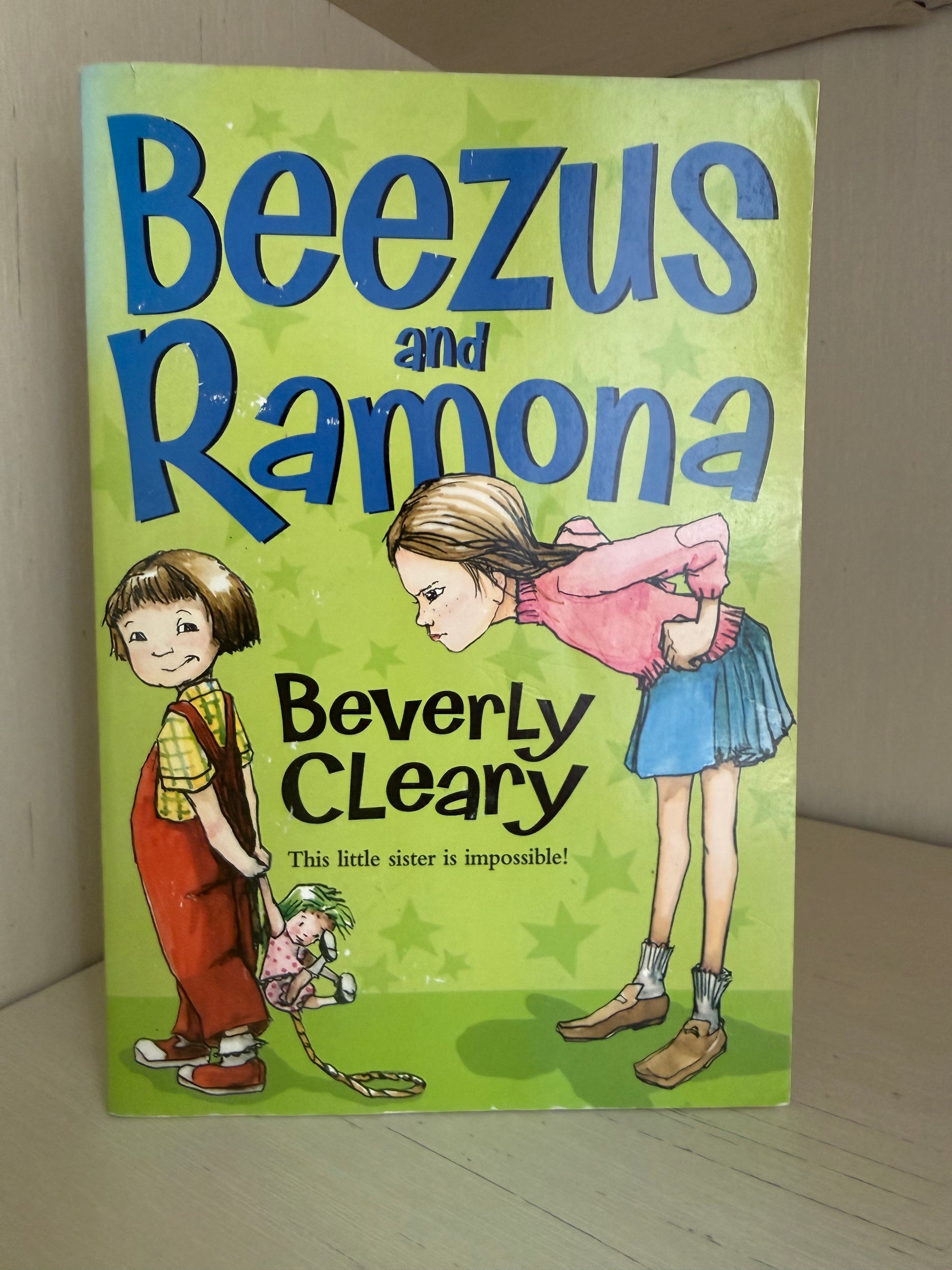 The front cover of the children's book 'Beezus and Ramona' by Beverly Cleary, featuring a bright lime green background with blue title text and cartoon illustrations of the two children.