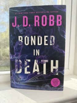 Book titled 'Bonded in Death' by J.D. Robb on a surface with a window in the background