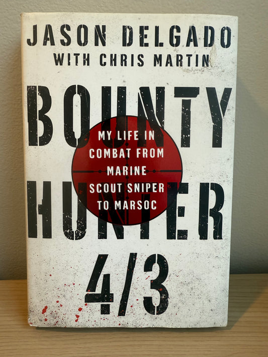 Book titled 'Bounty Hunter' by Jason Delgado with Chris Martin on a wooden surface.