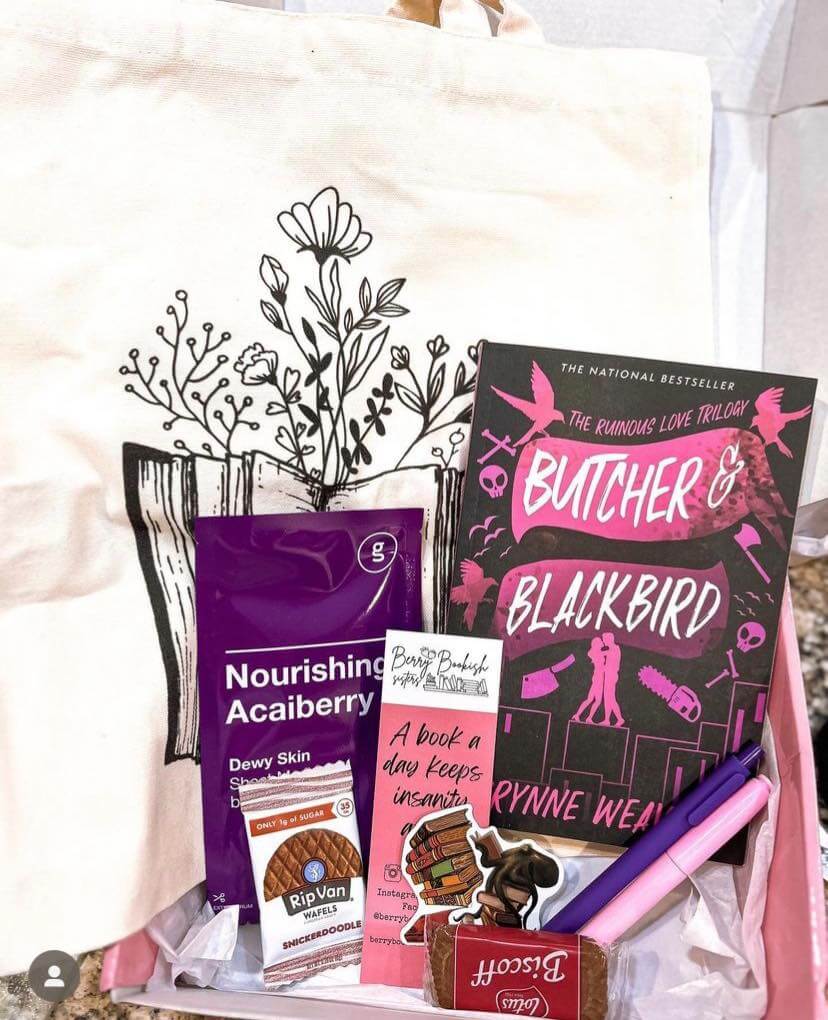 Gift basket with 'Butcher & Blackbird' book, snacks, and a tote bag with floral design.
