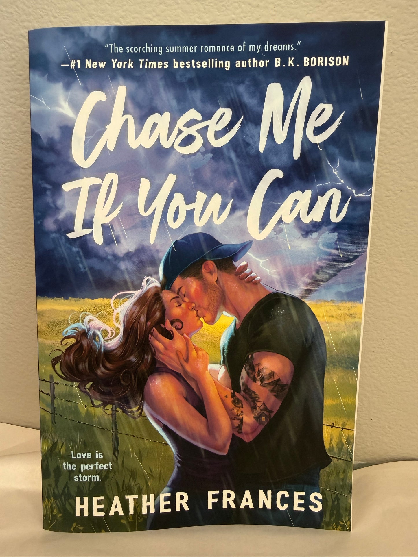 The book cover of 'Chase Me If You Can' by Heather Frances, featuring a romantic illustration of a couple embracing under a stormy sky, displayed on a neutral beige background.