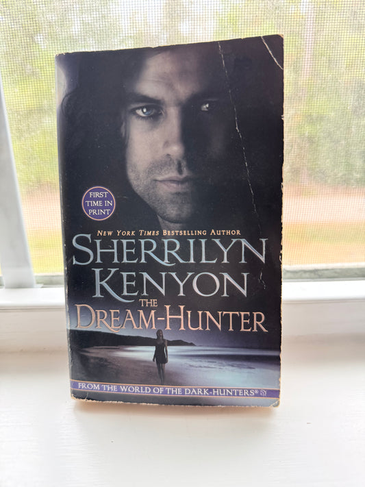 Book titled 'The Dream-Hunter' by Sherrilyn Kenyon on a surface with a window in the background