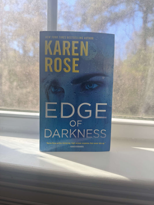 Book titled 'Edge of Darkness' by Karen Rose on a windowsill with a blurred outdoor background