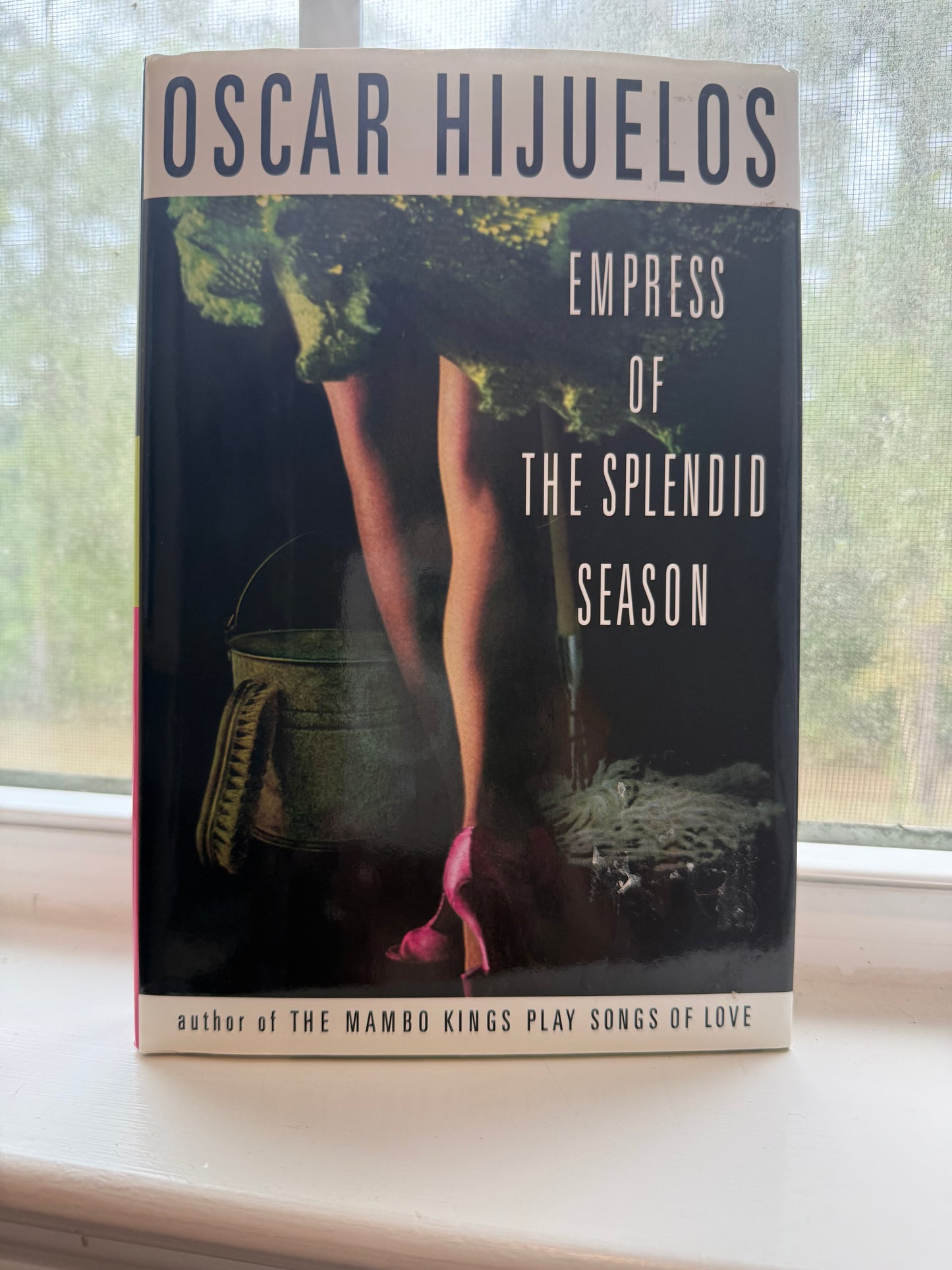 Book titled 'Empress of the Splendid Season' by Oscar Hijuelos on a window sill.