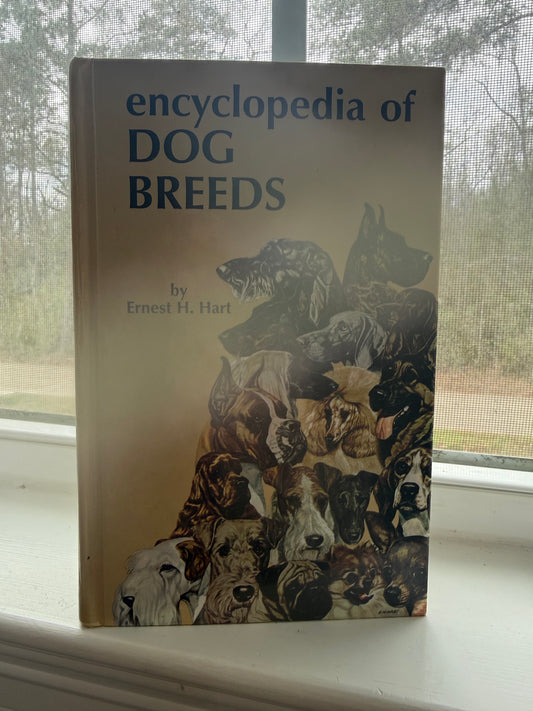 Book titled 'Encyclopedia of Dog Breeds' on a surface with a window in the background