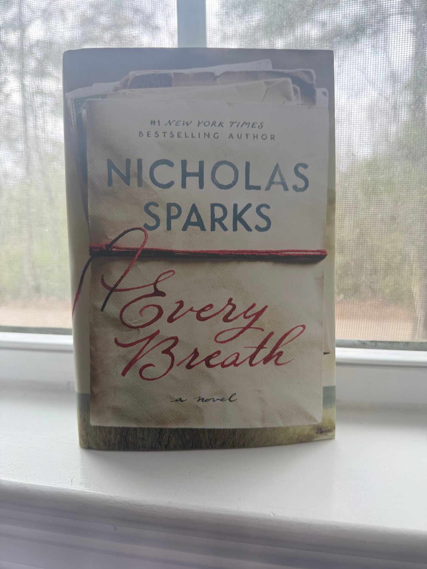 Book titled 'Every Breath' by Nicholas Sparks on a surface with a blurred background