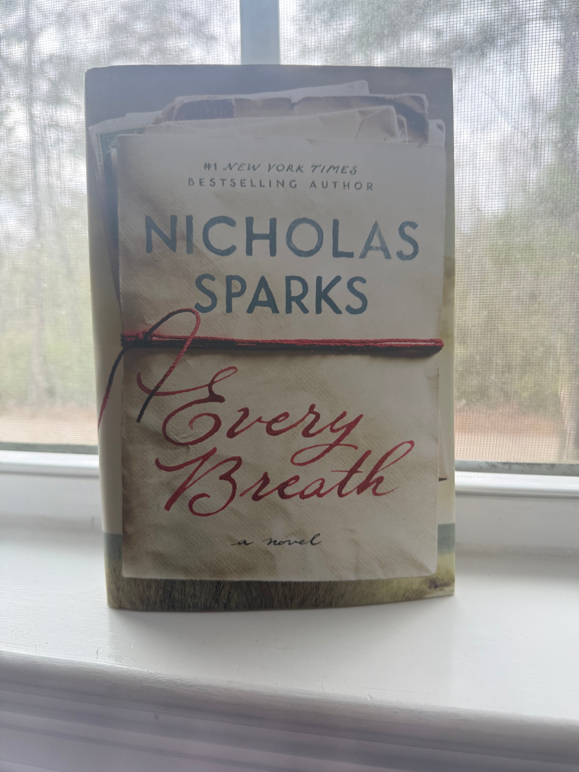Book titled 'Every Breath' by Nicholas Sparks on a surface with a blurred background