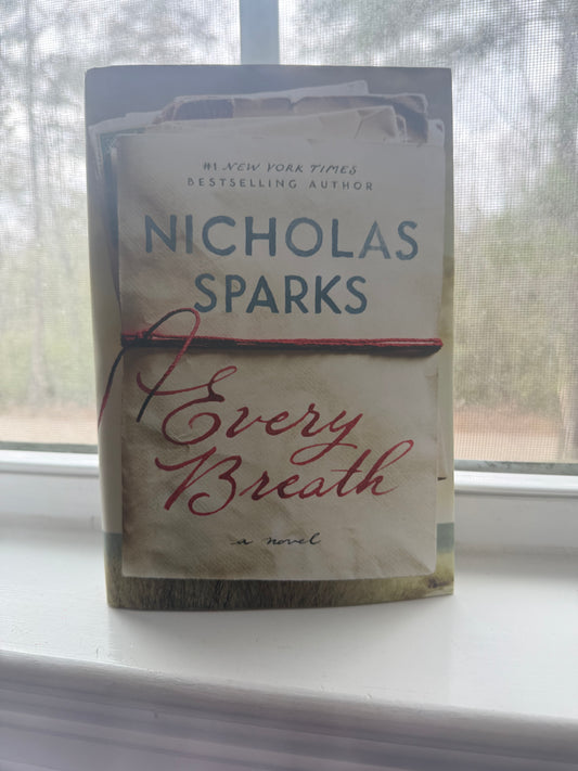Book titled 'Every Breath' by Nicholas Sparks on a surface with a blurred background