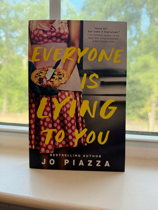 Book titled 'Everyone is Lying to You' by Jo Piazza on a window sill with a blurred outdoor background.