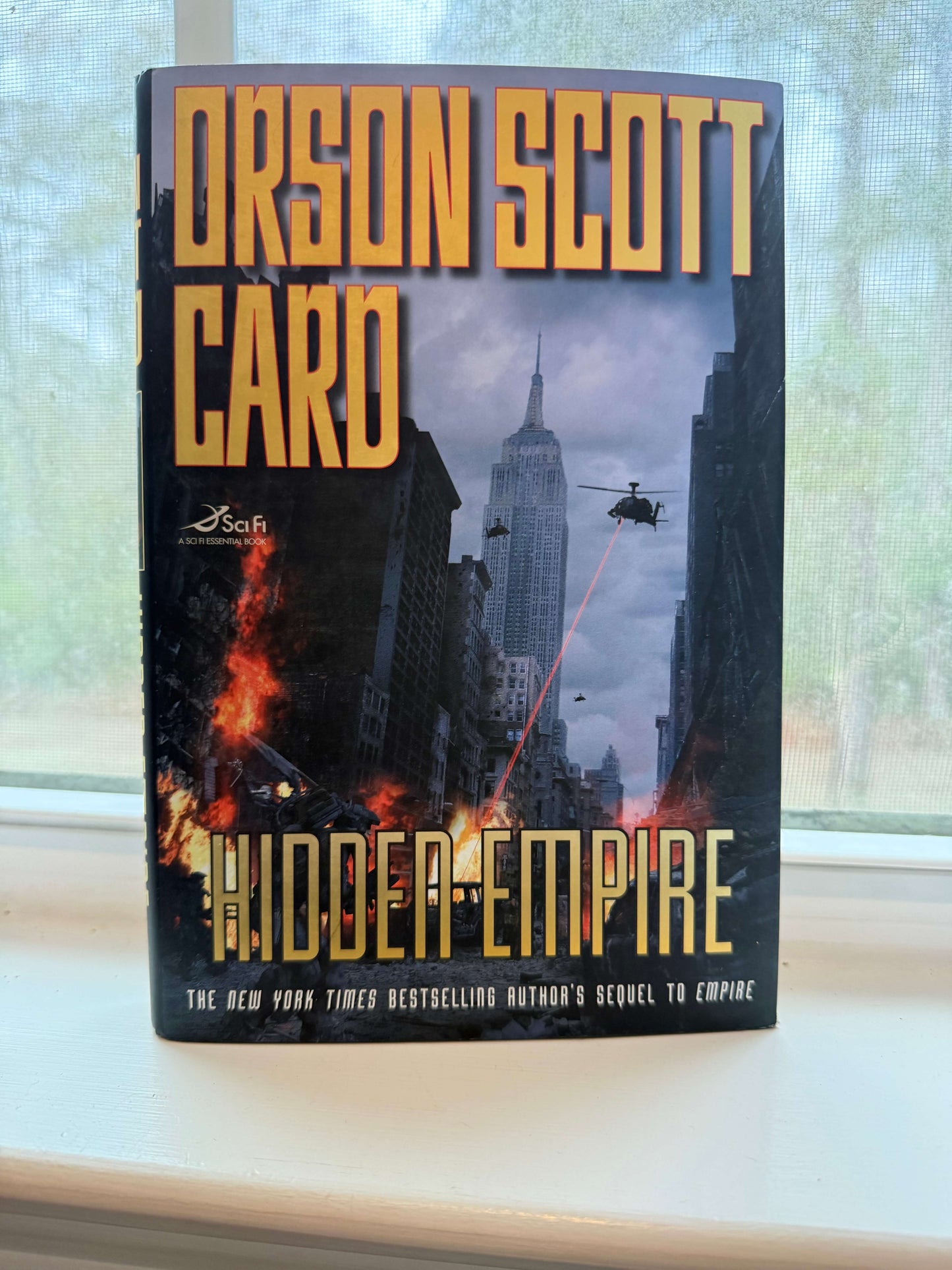 Book titled 'Hidden Empire' by Orson Scott Card on a reflective surface