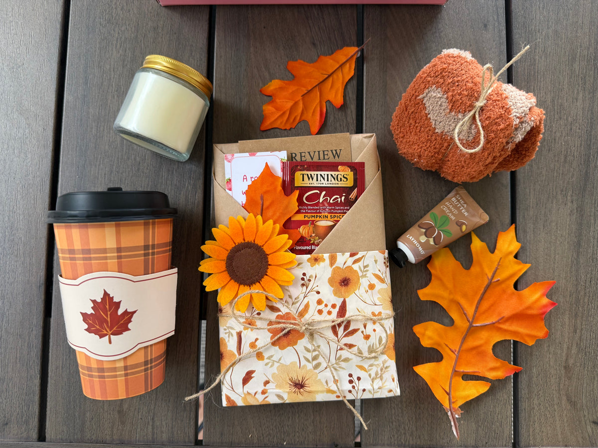 Cozy Up & Read Book Box with tea, candle, cozy socks, and autumn decorations on a table.