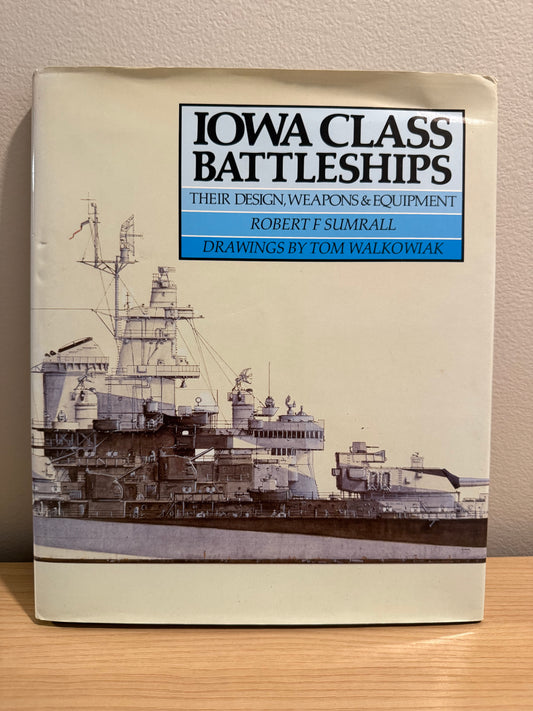 A book titled 'Iowa Class Battleships' by Robert F. Sumrall, with drawings by Tom Walkowiak, standing on a wooden surface against a beige wall.