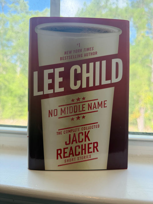 Book titled 'No Middle Name' by Lee Child on a surface with a window in the background