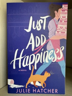 Cover with a woman caring a large cake titled Just Add Happiness.
