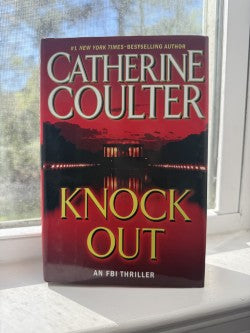 Book titled 'Knock Out' by Catherine Coulter on a windowsill.