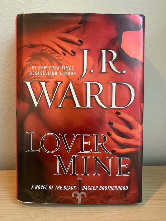 Book titled 'Lover Mine' by J.R. Ward on a light wooden surface.