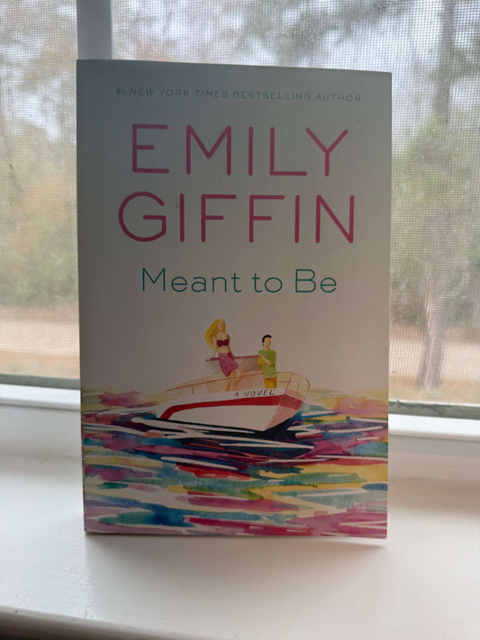 Book titled 'Meant to Be' by Emily Giffin on a windowsill with a blurred outdoor background