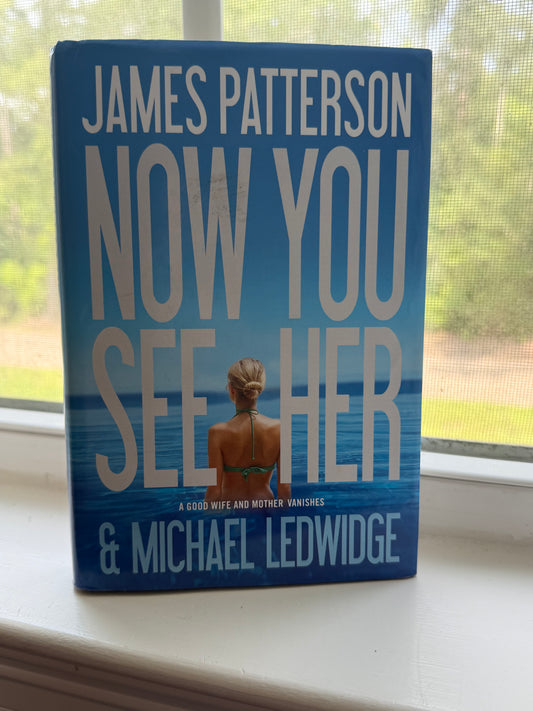 Book titled 'Now You See Her' by James Patterson and Michael Ledwidge on a surface with a window in the background.