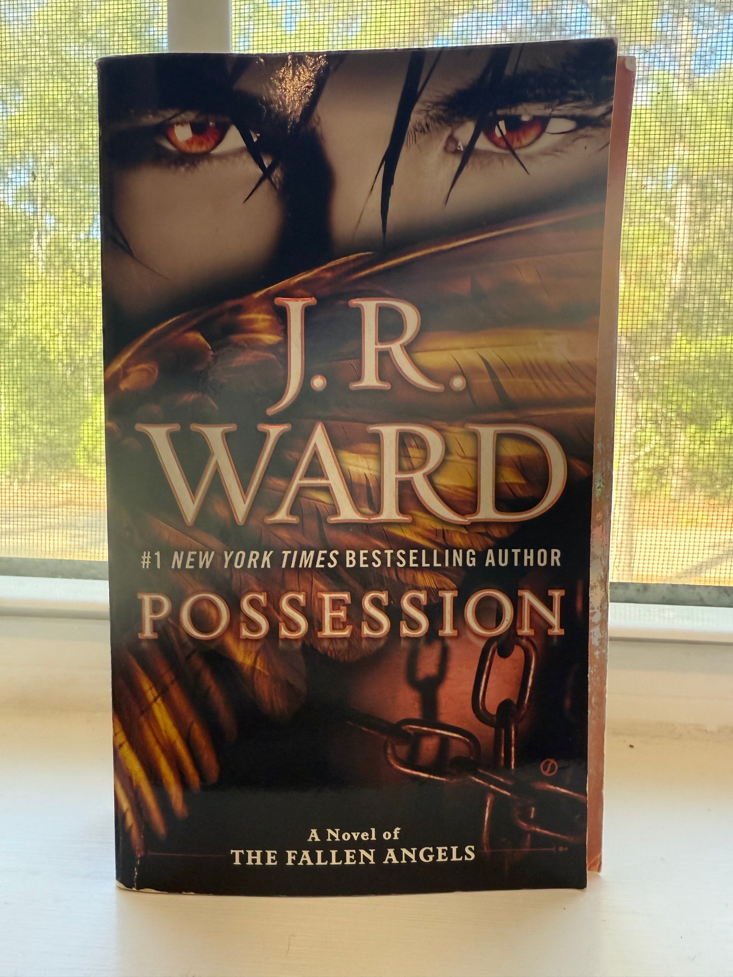 Book titled 'Possession' by J.R. Ward on a surface with a window in the background