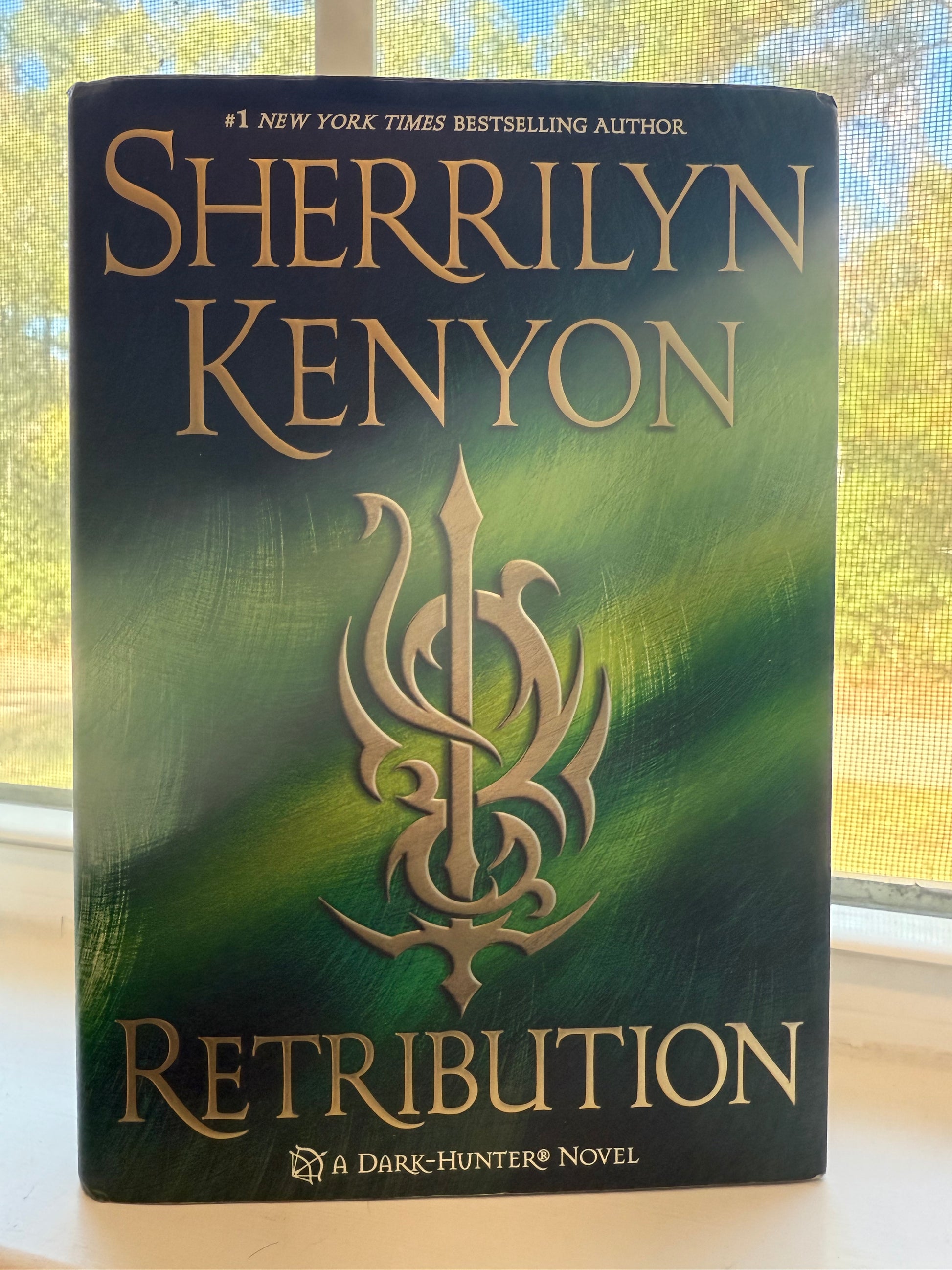 Book titled 'Retribution' by Sherrilyn Kenyon on a green and gold background