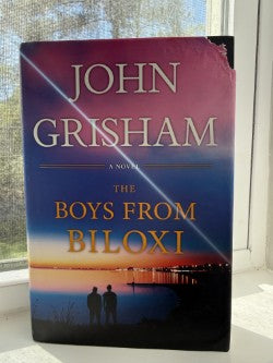 Book titled 'The Boys from Biloxi' by John Grisham on a reflective surface.