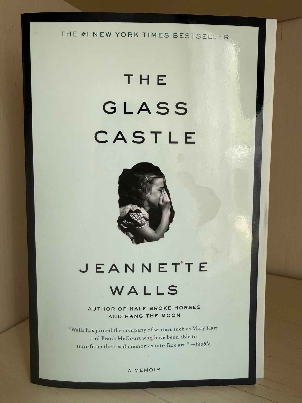 The front cover of the book 'The Glass Castle' by Jeannette Walls, photographed standing upright against a cardboard shipping box background.