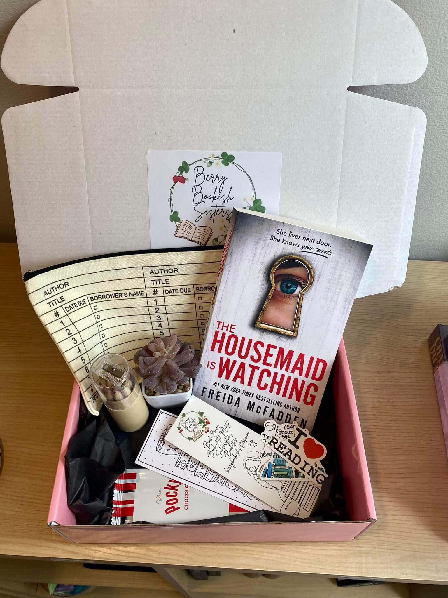 Book-themed gift box with 'The Housemaid is Watching' book and decorative items.