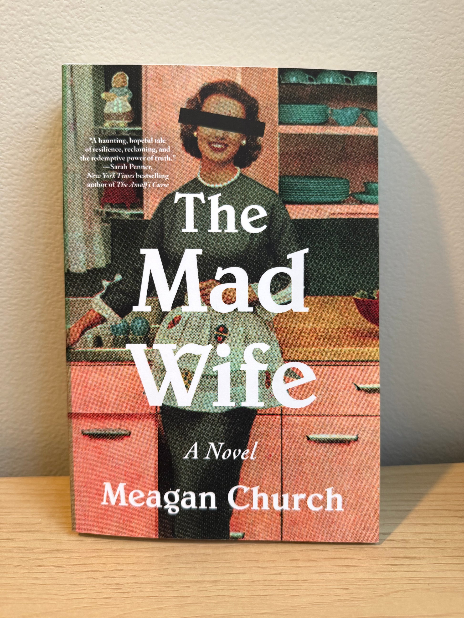 Book cover of 'The Mad Wife' by Meagan Church on a wooden surface.