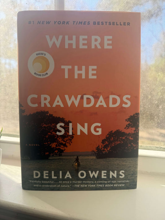 Book titled 'Where the Crawdads Sing' by Delia Owens on a windowsill.