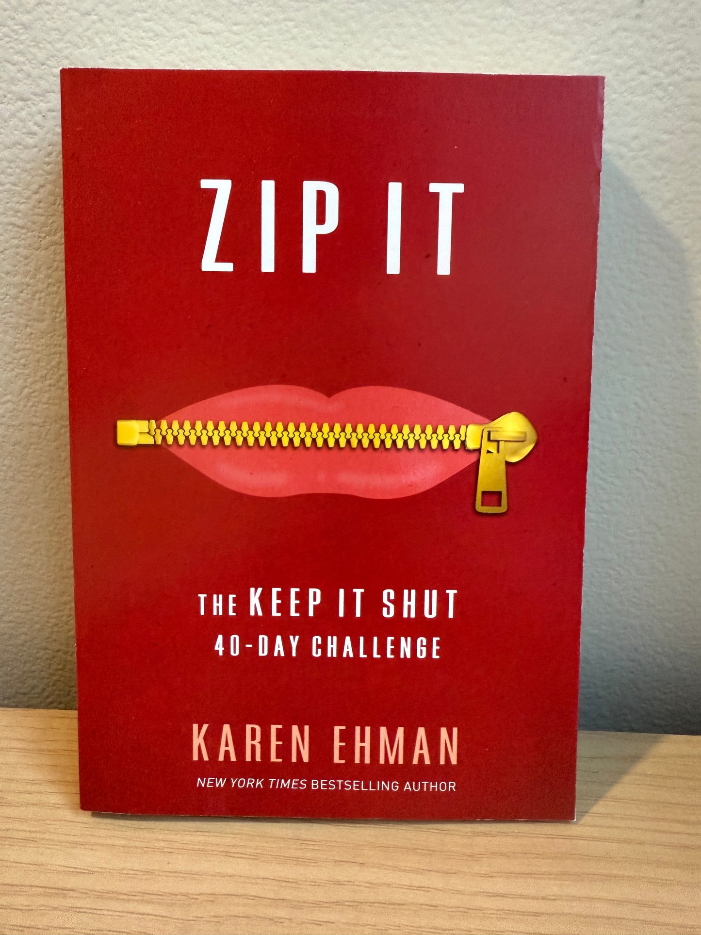 Book titled 'ZIP IT' by Karen Ehman with a red cover and gold zipper on a wooden surface.