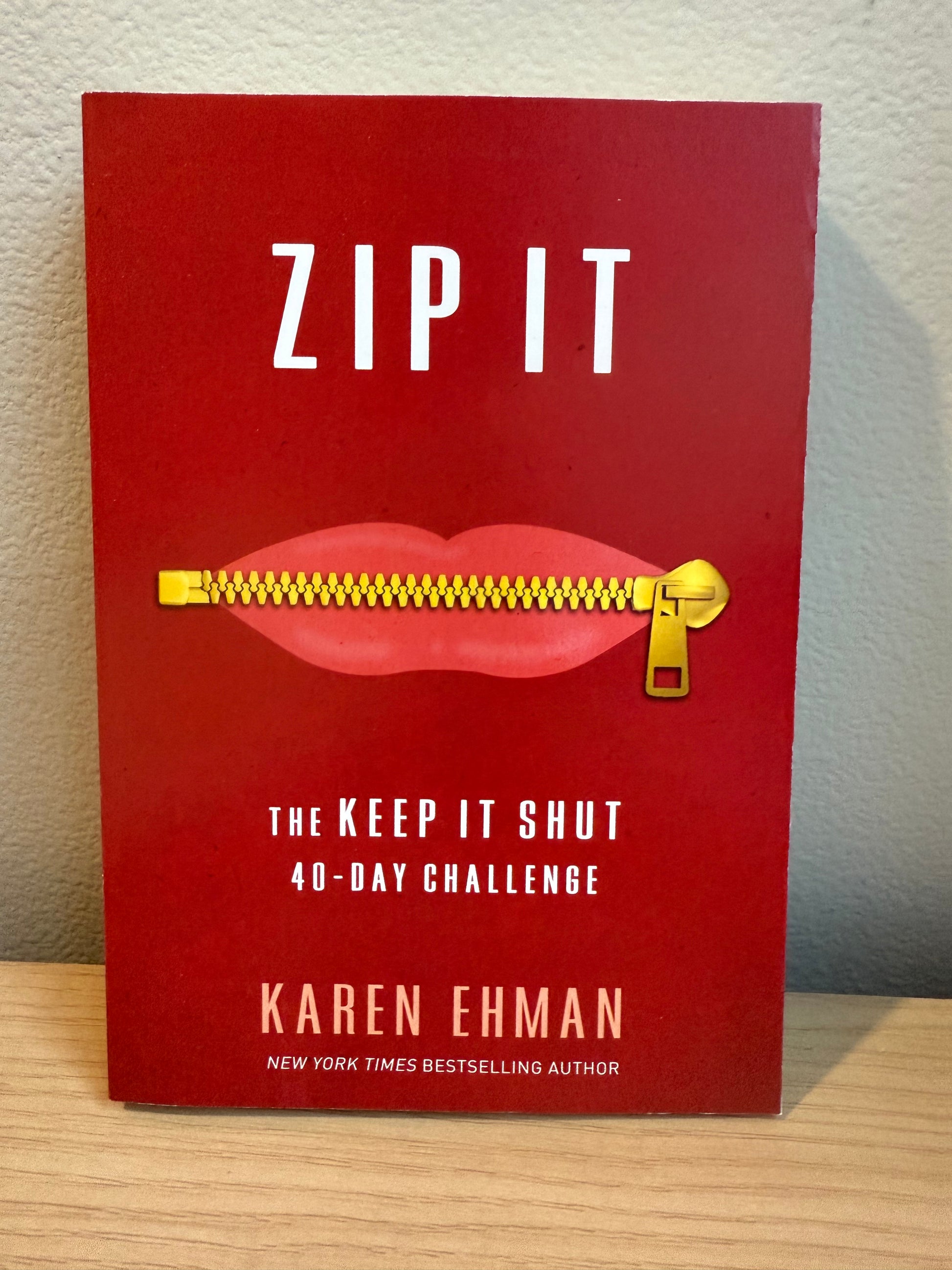 Book titled 'ZIP IT' by Karen Ehman with a red cover and gold zipper on a wooden surface.